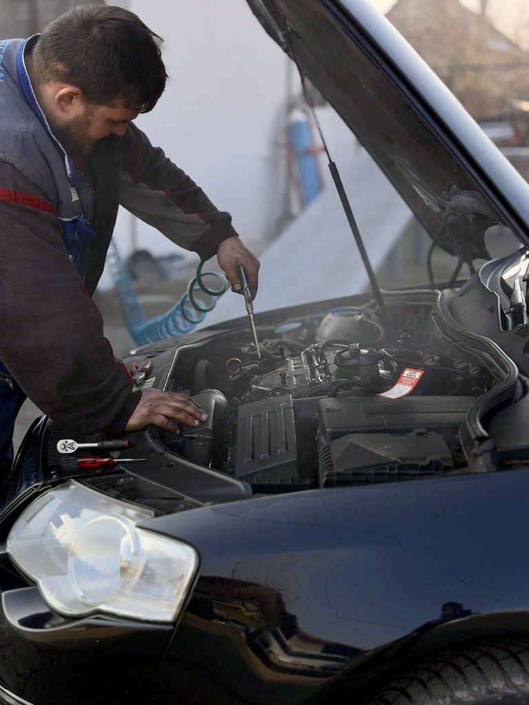 Skilled automotive technician repairing vehicle engine in workshop